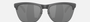 Oakley Frogskins Lite 51 round sunglasses for men in semi-rimless plastic, with grey frame, and black lenses. 63mm in lens size, 10mm in bridge size, and 138mm in temple length.
