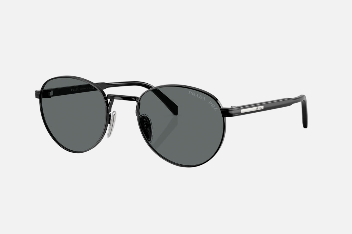 Prada PR B51S 1AB5Z1 oval sunglasses for men in full rim metal, with glossy black frame, and black lenses. 53mm in lens size, 21mm in bridge size, and 145mm in temple length.