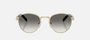 Prada PR B52S ZVN02C round sunglasses for women in full rim steel, with pale gold frame, and grey gradient lenses. 49mm in lens size, 21mm in bridge size, and 145mm in temple length.