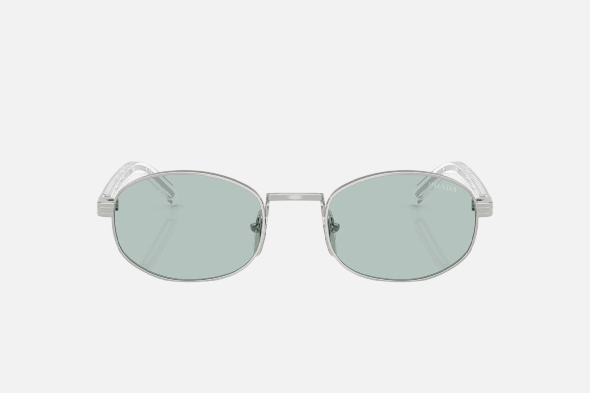 Prada PR B53S 1BC40N oval sunglasses for women in full rim steel, with silver frame, and sky blue lenses. 49mm in lens size, 21mm in bridge size, and 145mm in temple length.