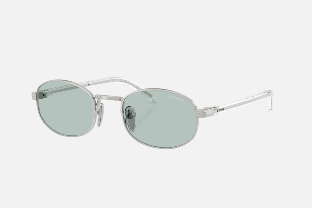 Prada PR B53S 1BC40N oval sunglasses for women in full rim steel, with silver frame, and sky blue lenses. 49mm in lens size, 21mm in bridge size, and 145mm in temple length.
