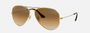 Ray-Ban RB3025 001/51 unisex's full rim aviator sunglasses in a gold metal frame with light brown lenses. Features a 62 mm lens size, 14 mm bridge size, and 135 mm temple length. Available in Dubai, UAE.