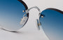 Eyepetizer Oxford C.1-53 round sunglasses for unisex in rimless steel, with silver frame, and blue gradient lenses. 51mm in lens size, 18mm in bridge size, and 145mm in temple length.